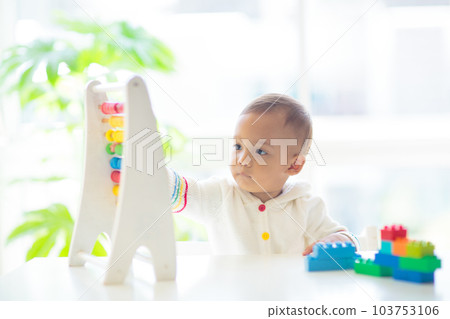 Baby boy playing with wooden abacus. 103753106