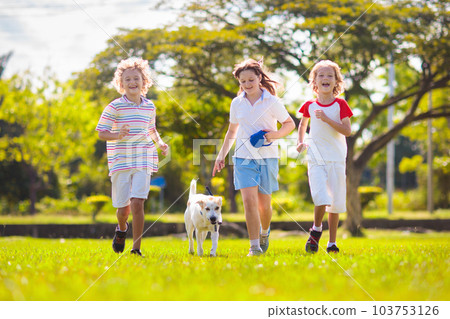 Kids play with dog. Children and puppy run in park 103753126
