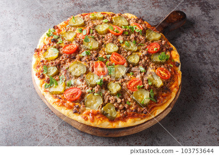 Tasty Pizza is topped with a creamy burger sauce, ground beef, cheese and pickles closeup on the wooden board. Horizontal Tasty Pizza is topped with a creamy burger sauce, ground beef, cheese and pickles closeup on the wooden board. Horizontal 103753644