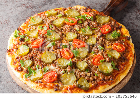 Cheeseburger Pizza is topped with a creamy burger sauce, ground beef, cheese and pickles closeup on the wooden board. Horizontal Cheeseburger Pizza is topped with a creamy burger sauce, ground beef, cheese and pickles closeup on the wooden board. Horizontal 103753646