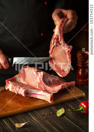 A professional chef cuts raw ribs on a cutting board before baking. Asian cuisine. Cooking delicious food in the kitchen 103754315
