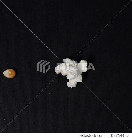 One grain of corn and one popcorn on a black background 103754452