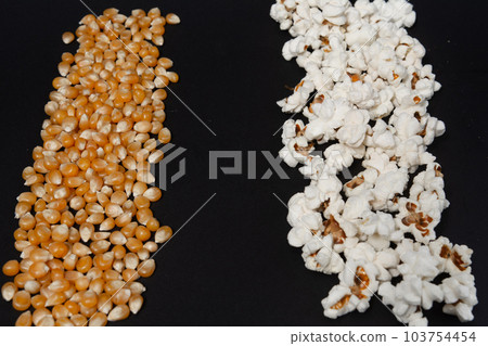 a row of ready-made popcorn and a row of corn kernels on a black background, place for inscription and advertising. 103754454