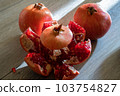 Two fresh ripe pomegranates and one cut on a gray wooden table 103754827