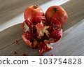 Two fresh ripe pomegranates and one cut on a gray wooden table 103754828