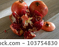 Two fresh ripe pomegranates and one cut on a gray wooden table 103754830