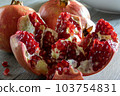Two fresh ripe pomegranates and one cut on a gray wooden table 103754831