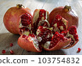 Two fresh ripe pomegranates and one cut on a gray wooden table 103754832