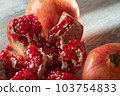 Two fresh ripe pomegranates and one cut on a gray wooden table 103754833