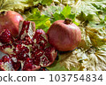 Two fresh ripe pomegranates and one cut on yellow autumn leaves 103754834