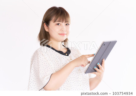 A young woman holding a tablet and looking at her business casual A young woman holding a tablet and looking at her business casual 103754934