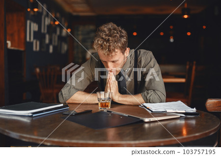 Man drinks whiskey. Businessman reads documents. Director in a shirt and suspenders. 103757195