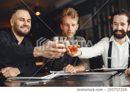 Businessmen in negotiations. Men with alcohol sitting at the table. Friends are talking. 103757208