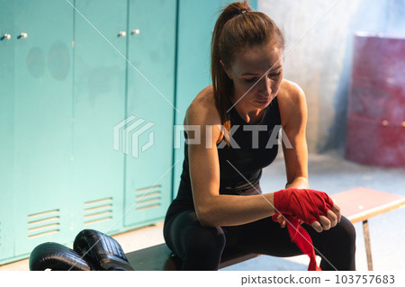 Women self defense girl power. Woman fighter preparing for fight wrapping hands with red boxing wraps sports protective bandages. Strong girl ready for fight active exercise sparring workout training 103757683