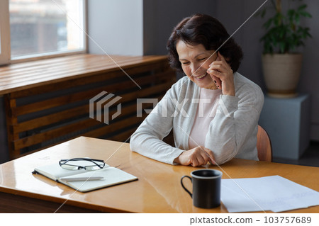 Happy middle aged senior woman talking on smartphone with family friends. Older mature lady with cell phone chatting with grown up children, resting in at home. Older generation modern tech usage Happy middle aged senior woman talking on smartphone with family friends. Older mature lady with cell phone chatting with grown up children, resting in at home. Older generation modern tech usage 103757689