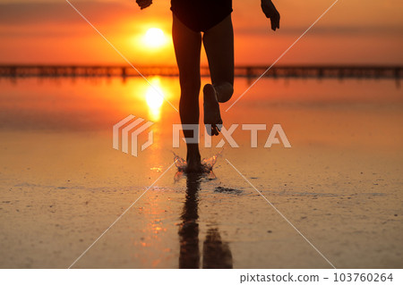 Active summer travel holiday. Cropped photo of legs silhouette of energy little child girl, boy having fun runs and plays on beach at sunset. Youth, lifestyle and happiness concept. Children's day Active summer travel holiday. Cropped photo of legs silhouette of energy little child girl, boy having fun runs and plays on beach at sunset. Youth, lifestyle and happiness concept. Children's day 103760264