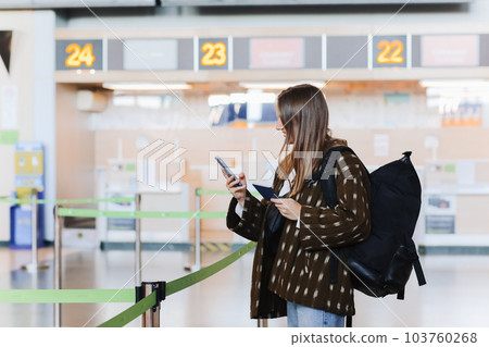 Travelling, vacation, tourism concept. Happy attractive young woman tourist showing passport at public airport terminal after check in at airline services desks, smiling, carrying backpack 103760268