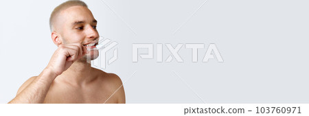 Young shirtless man taking care after teeth, brushing against white studio background. Banner 103760971