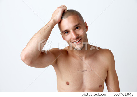 Well-being. Portrait of young attractive smiling man posing shirtless against white studio background. Perfect smile Well-being. Portrait of young attractive smiling man posing shirtless against white studio background. Perfect smile 103761043
