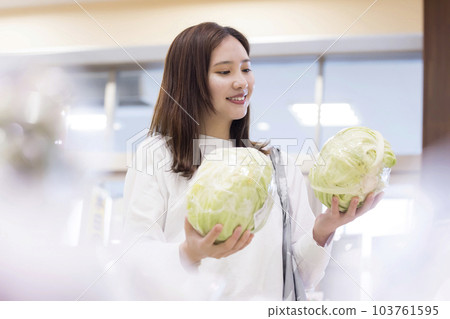 年輕女子在超市拿著白菜，選擇買哪一個 103761595
