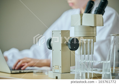 Young woman in lab coat entering experimental data 103761772