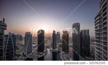 Tall residential buildings at JLT aerial night to day timelapse, part of the Dubai multi commodities centre mixed-use district. 103762545