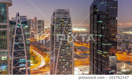 Tall residential buildings at JLT aerial day to night timelapse, part of the Dubai multi commodities centre mixed-use district. 103762547