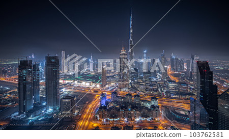 Panorama showing aerial view of tallest towers in Dubai Downtown skyline and highway night timelapse. 103762581