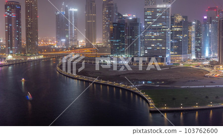 Cityscape of skyscrapers in Dubai Business Bay with water canal aerial day to night timelapse 103762600