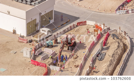 Group of worker and red excavator diging water drainage at construction site aerial timelapse. 103762608