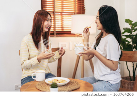 Young woman lesbian couple eating snack and drinking hot chocola 103764206