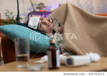Sick ill woman suffering from cold or allergy sitting on home sofa sneezes wipes snot into napkin Sick ill woman suffering from cold or allergy sitting on home sofa sneezes wipes snot into napkin 103764213