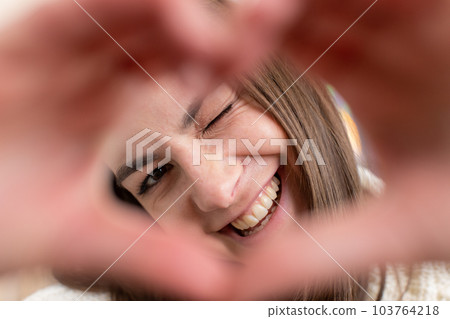 Happy young woman girl makes symbol of love showing heart sign to camera express romantic feelings Happy young woman girl makes symbol of love showing heart sign to camera express romantic feelings 103764218