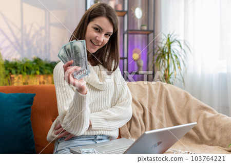 Smiling happy woman counting money cash and use laptop pc calculate domestic income earnings at home 103764221