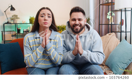Young family marriage couple praying sincerely with folded arms asking God for help, begging apology 103764260