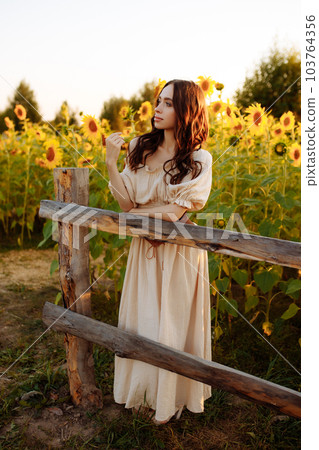 Beautiful woman in a dress in a field of sunflowers Beautiful woman in a dress in a field of sunflowers 103764356