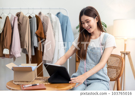 Female online seller is checking online clothes orders on tablet after using smartphone to broadcast live Female online seller is checking online clothes orders on tablet after using smartphone to broadcast live 103765016