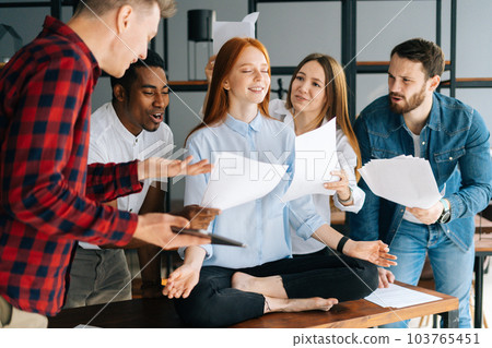 Side view of calm young business woman meditate at business meeting avoiding pressure annoying angry colleagues. Meditative female doing yoga for stress relief. Coworkers shaking paper documents. 103765451