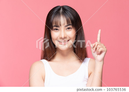 Young Beautiful Asian woman smile with clean and fresh skin Happiness and cheerful with positive emotional pointing up,isolated on pink background,Beauty Cosmetics and spa Treatment Concept 103765536