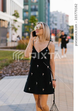 Happy woman with a phone talking on the phone on the street 103770162