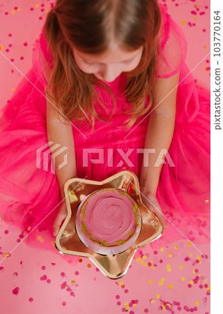 Girl in a pink dress holds in her hands a delicious sweet bento cake on a golden plate in the form of a star. Portioned trendy desert for one person Girl in a pink dress holds in her hands a delicious sweet bento cake on a golden plate in the form of a star. Portioned trendy desert for one person 103770164