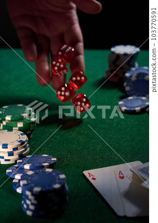 there are red dice and poker chips on the green cloth 103770591
