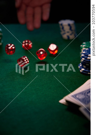 there are red dice and poker chips on the green cloth 103770594