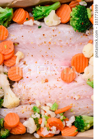 Raw sea bass fish fillet with salt, spices and vegetables in a baking dish 103771699