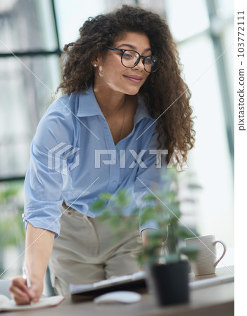 woman makes a report in the office. Woman writing notes for educational project in business woman makes a report in the office. Woman writing notes for educational project in business 103772111