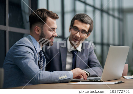 Two young businessmen sitting at workplace and working together in office 103772791