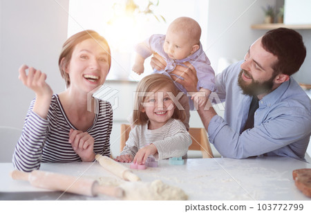 Young parents playing with children in the kitchen Young parents playing with children in the kitchen 103772799