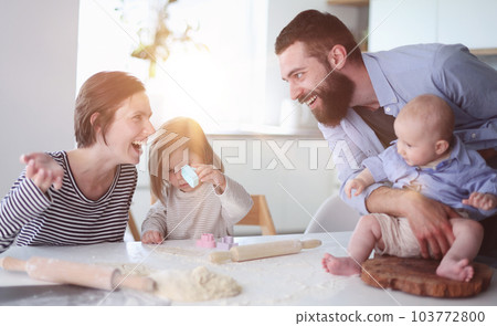 Young parents playing with children in the kitchen Young parents playing with children in the kitchen 103772800