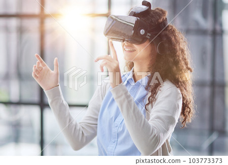 positive woman wearing virtual reality goggles headsetConnection, technology, new generation, progress concept. positive woman wearing virtual reality goggles headsetConnection, technology, new generation, progress concept. 103773373