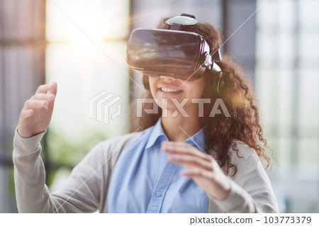 positive woman wearing virtual reality goggles headsetConnection, technology, new generation, progress concept. positive woman wearing virtual reality goggles headsetConnection, technology, new generation, progress concept. 103773379